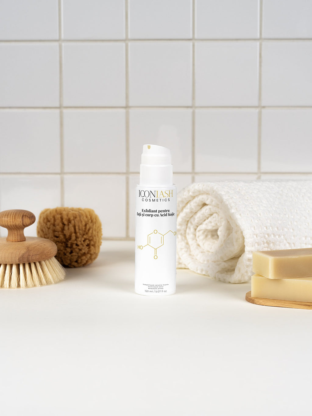 Exfoliantul IconLash cu acid kojic într-o baie, lângă prosop, perie și săpun
